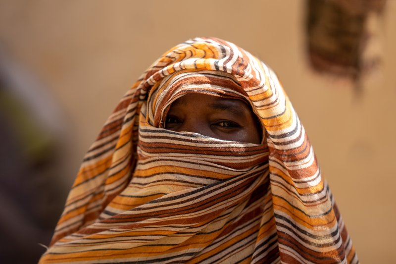 A woman wearing a headscarf looks to camera, only her eyes are visible