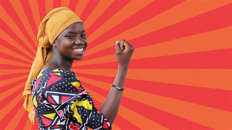 A woman holding a stretcher made out of two sticks - another women is just about visible in the background carrying the other end of the stretcher